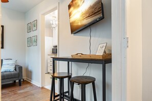 Ett modernt vardagsrum med en soffa, en tv som är monterad på väggen och ett skrivbord med pallar.