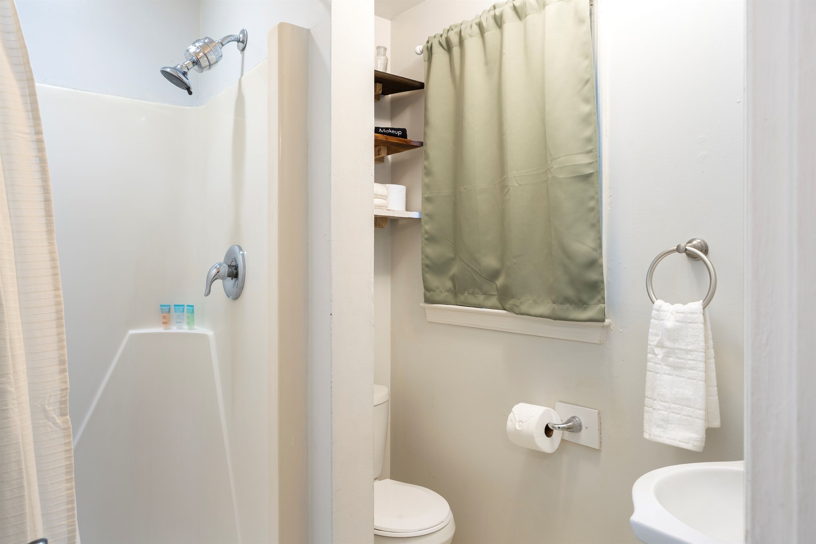 Un baño con ducha, inodoro, lavamanos y un perchero para toallas.