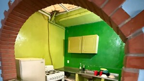 Een keuken met een gasfornuis, een koelkast en een groene wand.