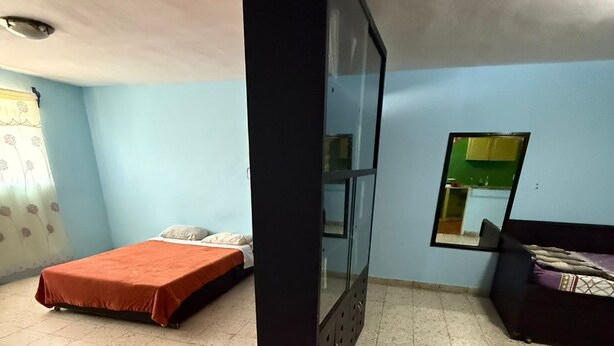Een kamer met een bed, een spiegel en een kledingkast.