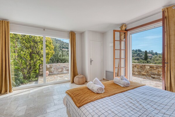A bedroom with a bed, a large window, and a view of the outdoors.