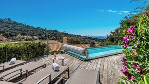 Ein Pool auf dem Dach mit Liegestühlen und einem Tisch, umgeben von Grün und mit Blick auf eine hügelige Landschaft.