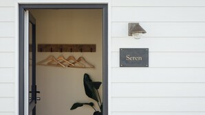 A door with a coat rack, a sign reading 'Seren,' and a wall-mounted light fixture. - Riverside living, reimagined above the Teifi (Cardigan)
