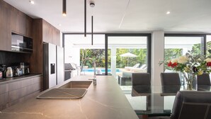 Et moderne køkken med marmor bordplade, indbyggede apparater og udsigt til en pool.