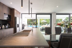 A modern kitchen with a marble countertop, built-in appliances, and a view of a pool. - Villa Karma -Elegant Villa with Pool, Garden & Mul (Benahavís)