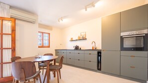 A modern kitchen with grey cabinets, a dining table with chairs, and a built-in oven. - Puebla Aida Unique - Charming Renovated 2 bedroom (Mijas Costa)