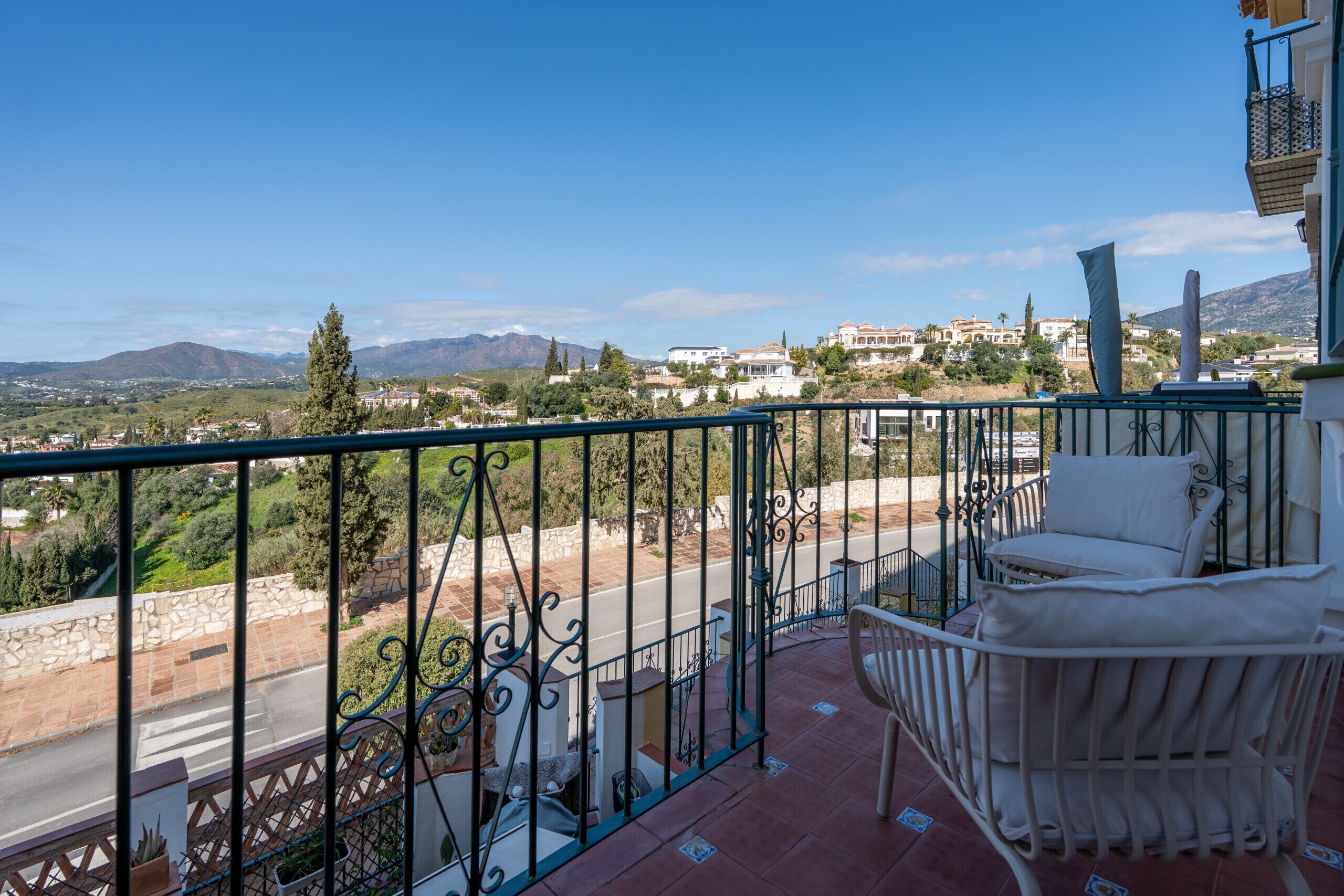 Ein Balkon mit Blick auf eine Straße, Bäume und entfernte Gebäude.