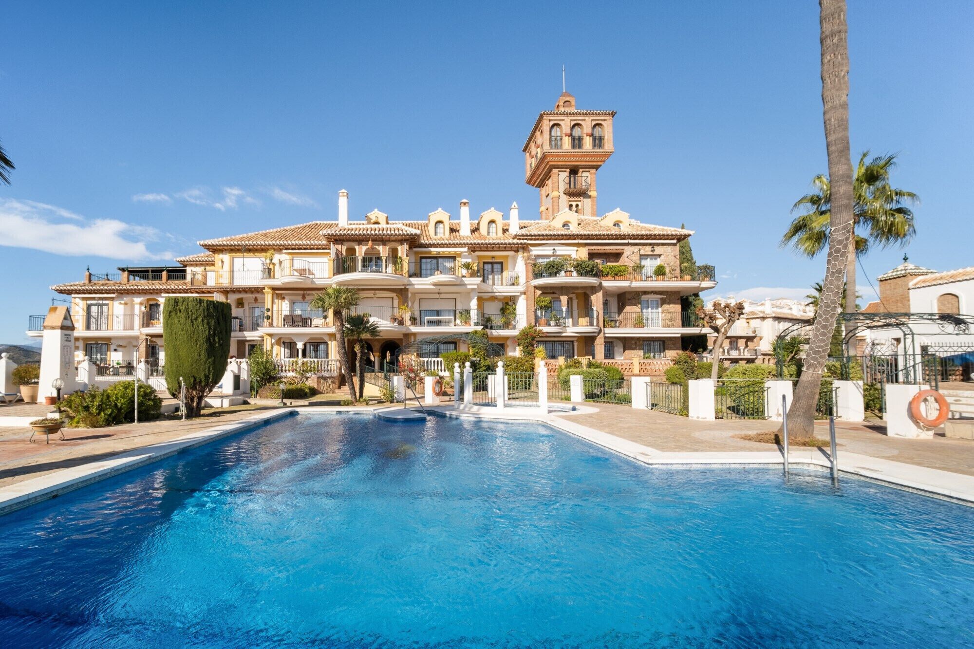Un grand hôtel à plusieurs étages, avec une piscine en premier plan.