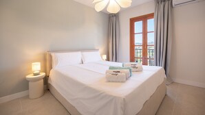 A hotel room with a bed, bedside lamp, curtains, and a view through a window. - Puebla Aida Unique - Charming Renovated 2 bedroom (Mijas Costa)