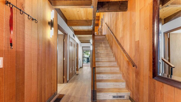 A wooden interior hallway with a staircase, wooden walls, and a metal handrail. - Renovated Condo w/ Pool, Near Lake Tahoe & Beach (Kings Beach)