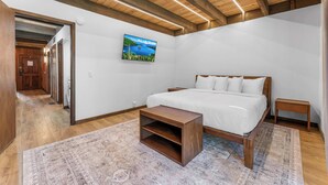 A bedroom with a bed, wooden nightstands, a small wooden table, a rug, and a painting on the wall. - Renovated Condo w/ Pool, Near Lake Tahoe & Beach (Kings Beach)