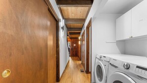 A laundry room with a washing machine and dryer, wooden flooring, and a wooden ceiling. - Renovated Condo w/ Pool, Near Lake Tahoe & Beach (Kings Beach)