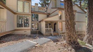 A multi-story building with a wooden exterior, a covered porch, and a staircase leading to the entrance. - Renovated Condo w/ Pool, Near Lake Tahoe & Beach (Kings Beach)