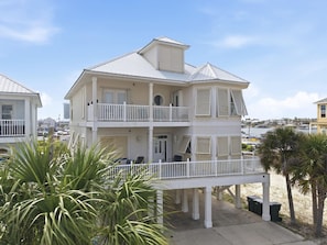 Ein mehrstöckiges Strandhaus mit Balkonen, einer überdachten Veranda und Blick auf den Ozean.
