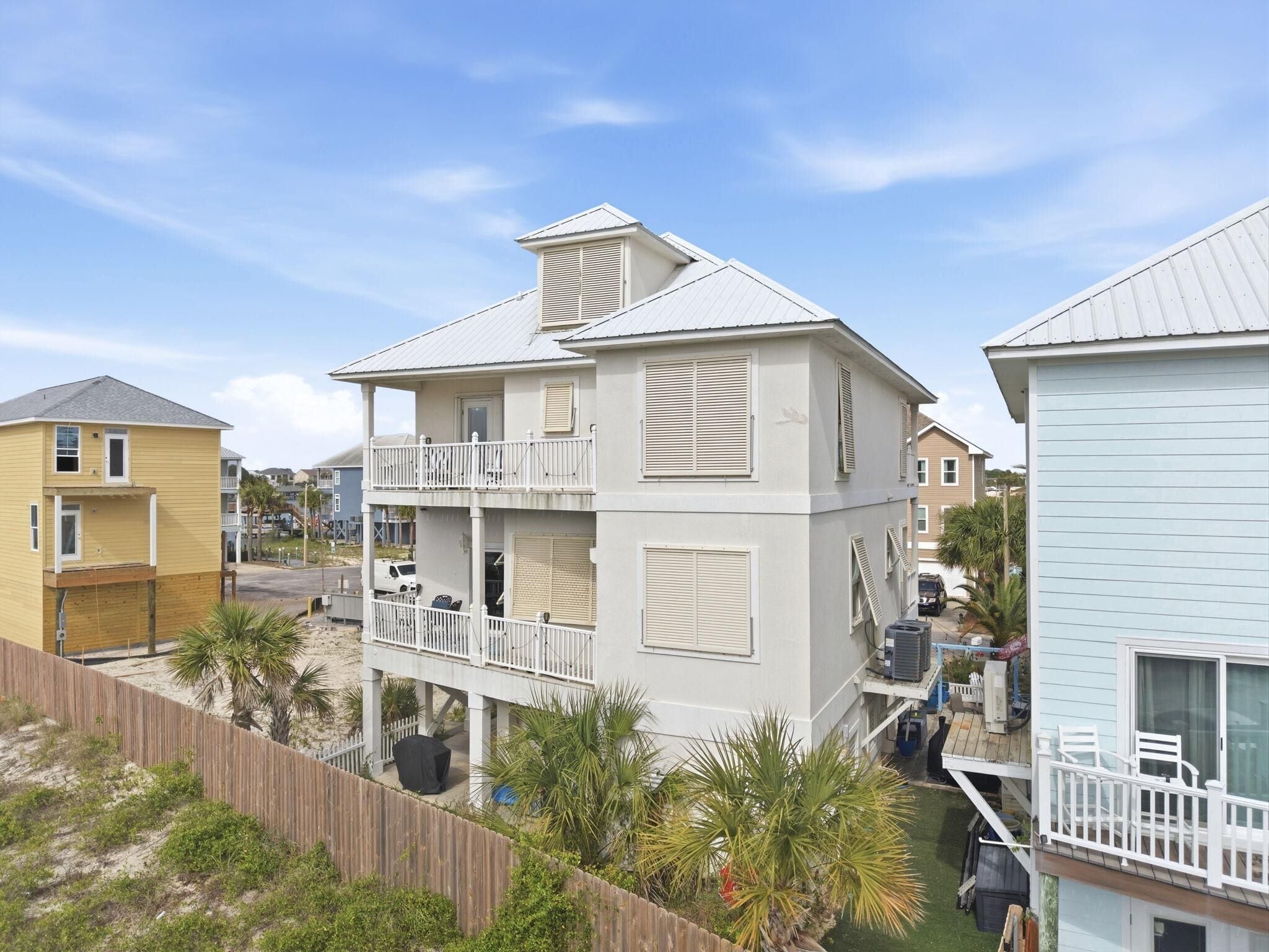 A multi-story building with a balcony, a covered outdoor area, and a fenced yard.