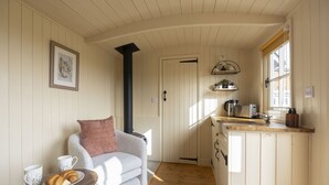 Ein gemütliches Zimmer mit einer Couch, einem kleinen Tisch mit Croissants und Kaffeetassen, einer Küchenzeile mit Spüle und Toaster sowie einem gerahmten Bild an der Wand.
