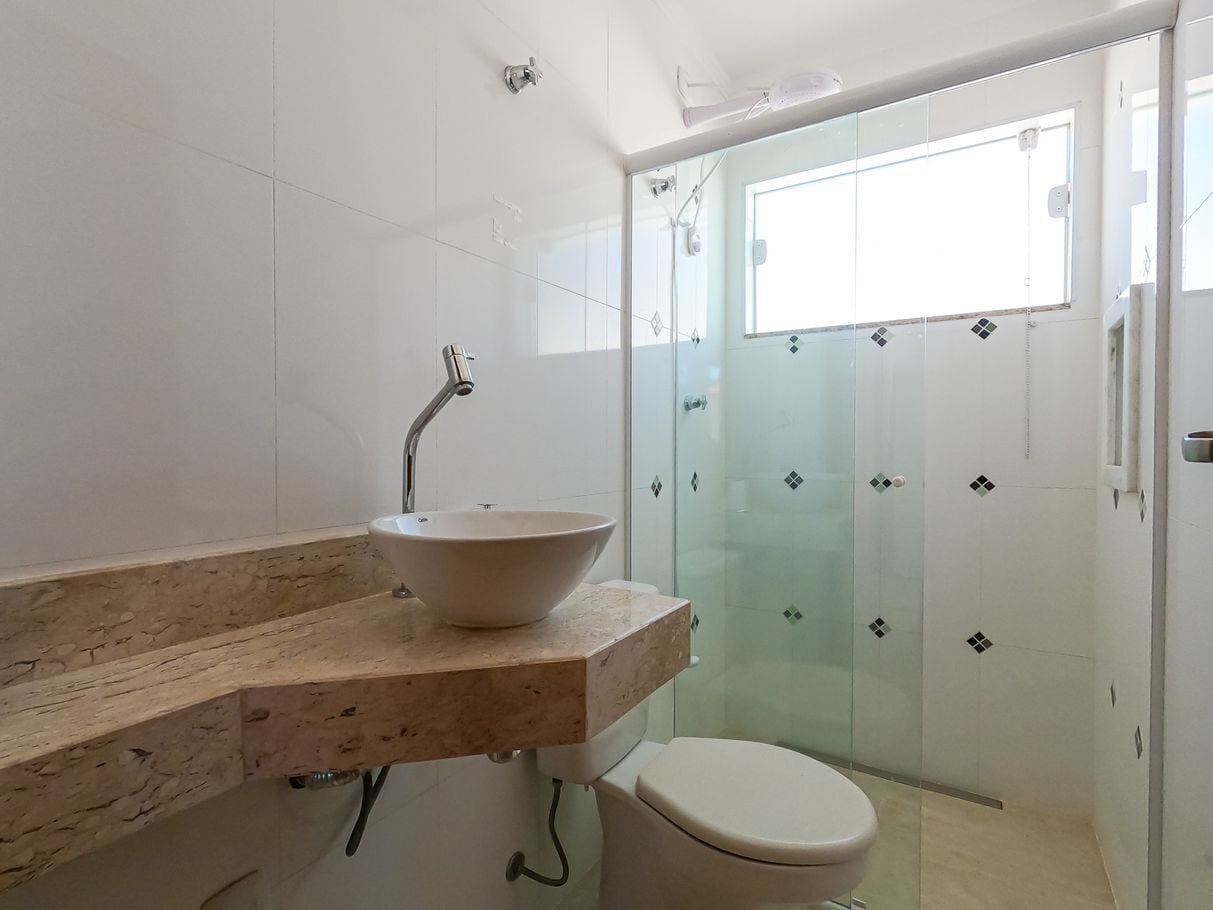 Une salle de bain avec un grand lavabo en forme de cuvette, des toilettes et une cabine de douche en verre.