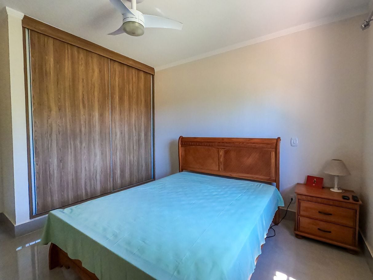A bedroom with a bed, a nightstand, a lamp, and a ceiling fan.