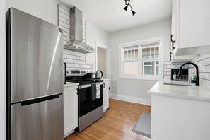 Una cucina moderna con elettrodomestici in acciaio inossidabile, mobili bianchi e una finestra che offre luce naturale.