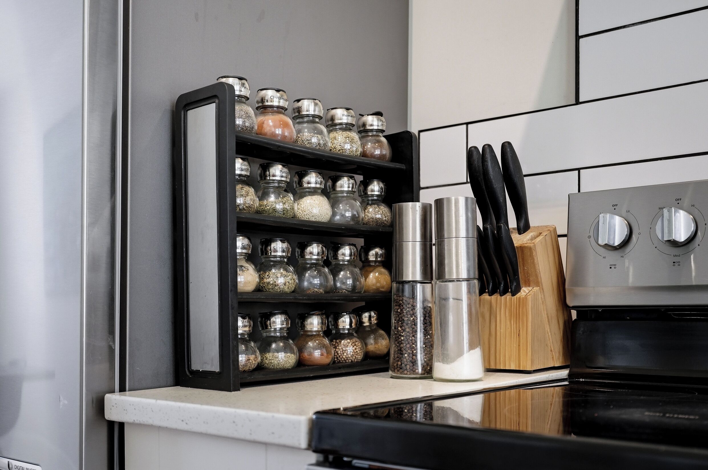 A kitchen with a spice rack, a stainless steel kettle, and a knife block.