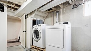 A laundry room with two washing machines and a door leading to another room. - Comfortable Crescentwood Bungalow | 3 Bed | 2 Bath | (Winnipeg)