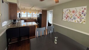 Una cucina con isola centrale, mobili in legno, ventola a soffitto e un'opera d'arte a tema floreale al muro.