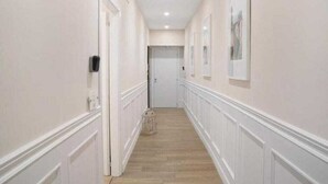 A hallway with white walls, a wooden floor, and a door at the end. - Pompeii luxury suite - near ruins (Pompei)