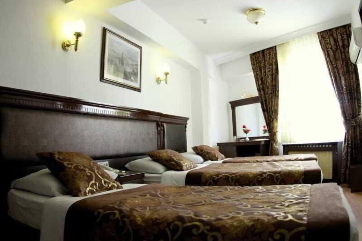 A hotel room with two beds, a wooden headboard, a large mirror, and a window with curtains.