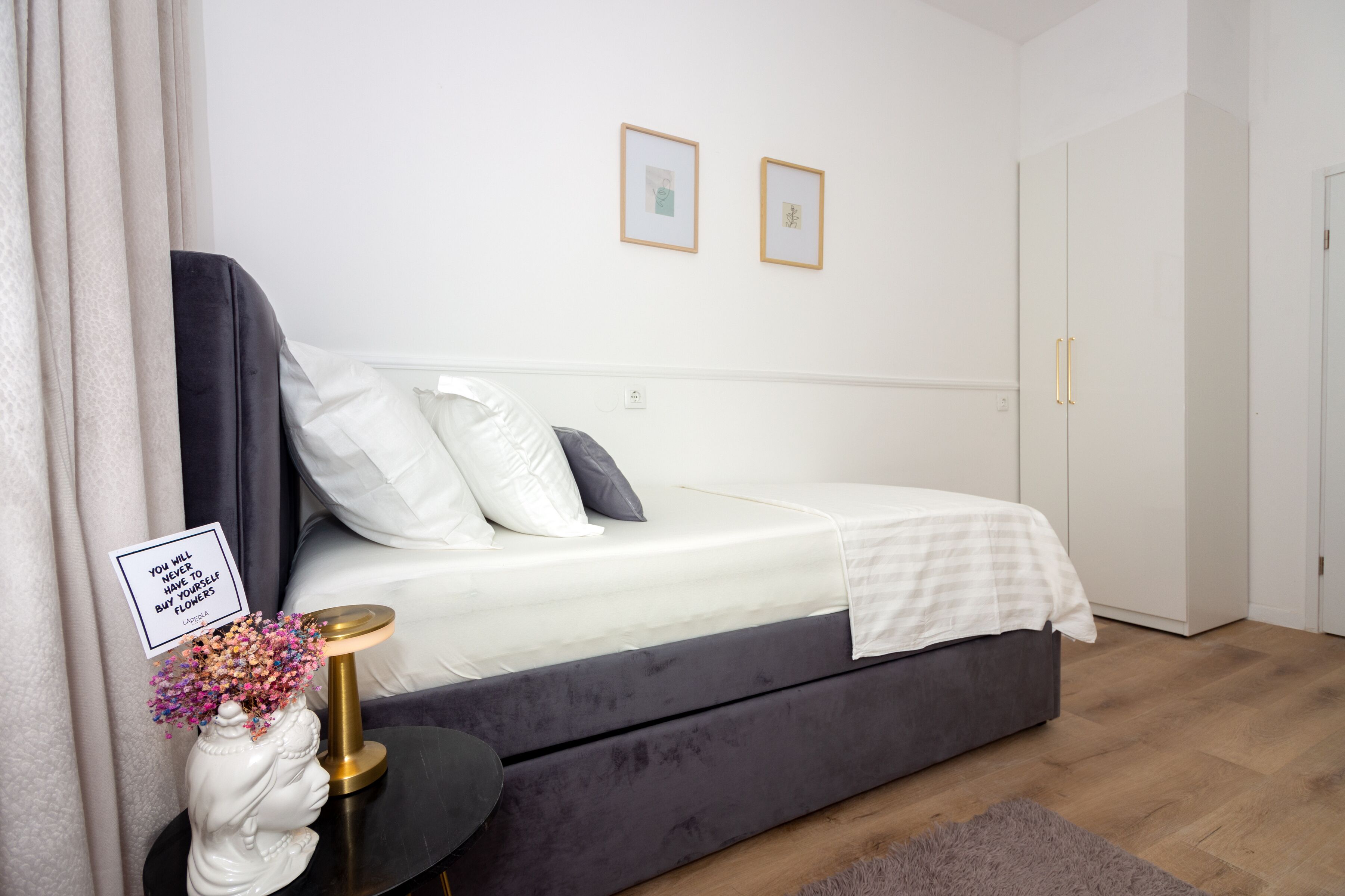 A bedroom with a bed, bedside table, and a wall-mounted picture frame.