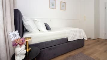 A bedroom with a bed, bedside table, and a wall-mounted picture frame.