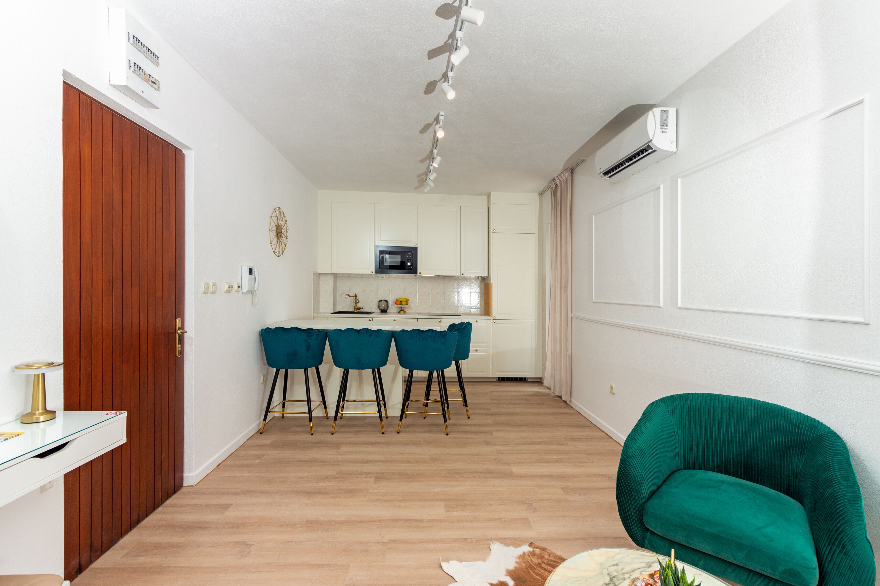 A modern kitchen with white cabinets, a microwave, and a dining area with blue chairs.