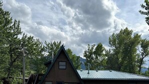 Eine Holzhütte mit einem Metalldach, einer Terrasse und einem Rasen.