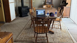 Ein Essbereich mit einem runden Tisch, Stühlen, einem Laptop und einer Wasserflasche.
