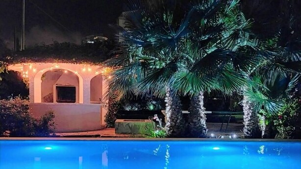 A swimming pool with a clear blue water surface, surrounded by a white building with arches and a palm tree. - Villa Chalet Benidorm -  Private pool, AirCon, Walk to city centre and beaches (Benidorm)