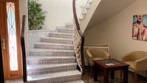 A staircase with patterned tiles, a chair, a small table, and a painting on the wall. - Villa Chalet Benidorm -  Private pool, AirCon, Walk to city centre and beaches (Benidorm)