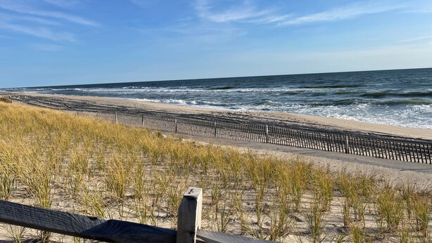 A beach with a wooden walkway and sand dunes.