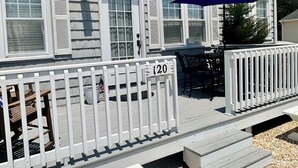 A house with a covered porch, a number sign '120' on the railing, and a patio area with a table and chairs.