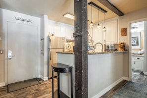 A kitchen with a stainless steel refrigerator, a wooden island, pendant lights, and a white door with a sign.