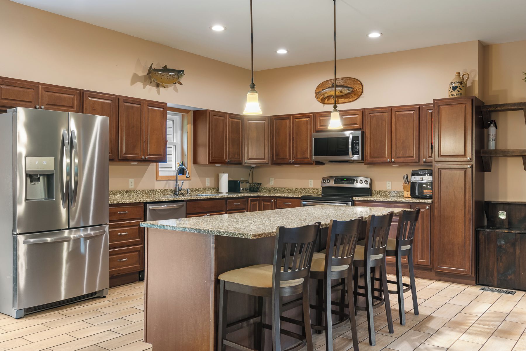 A modern kitchen with stainless steel appliances, wooden cabinets, and a granite countertop.