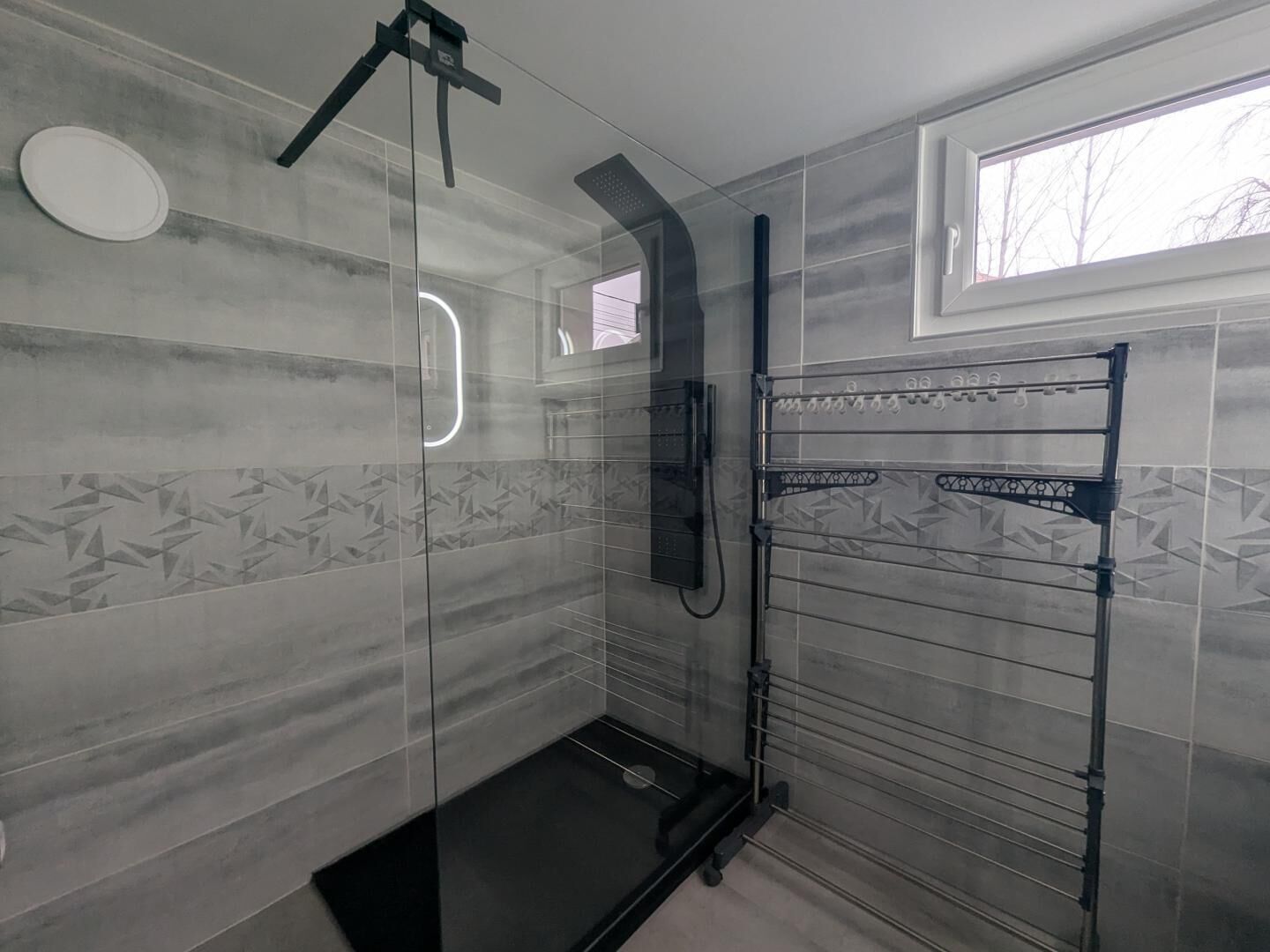 A modern shower area with a glass enclosure, a handheld showerhead, and a wall-mounted towel rack.