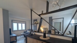 A modern living room with a sofa, a coffee table, and a dining area with a wooden cabinet and a black countertop.