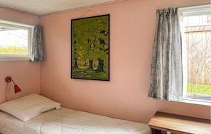 Ein Schlafzimmer mit Bett, einem Bild, einem Fenster mit Vorhängen und einem Nachttisch.