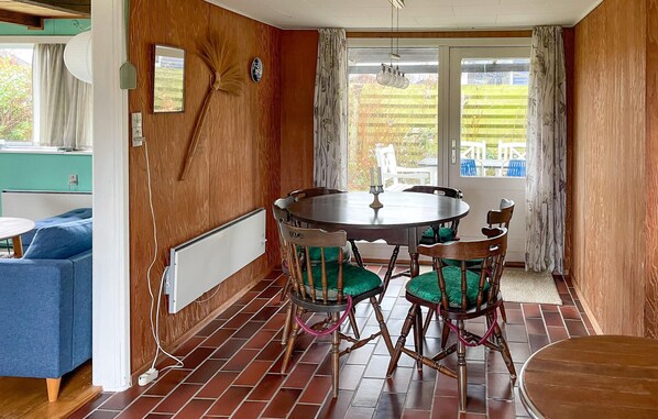 Een eetruimte met een ronde tafel, houten stoelen en uitzicht op de tuin via een glazen deur.