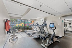 A gym with treadmills, exercise bikes, and a view of outdoor playgrounds. - Oceanfront Condo with Lazy River (Myrtle Beach)