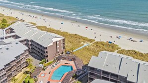 Un hôtel situé sur la côte, offrant une vue sur la plage, une piscine et plusieurs balcons.