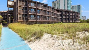 Un hôtel à plusieurs étages doté de balcons, situé en bord de mer, avec un ciel dégagé.