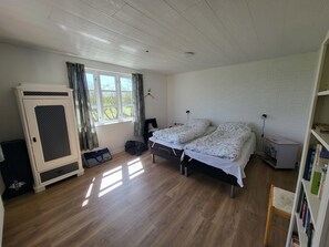 Makuuhuoneessa on kaksi sänkyä, vaatekaappi, ikkuna verhoilla, kirjahylly ja patteri.