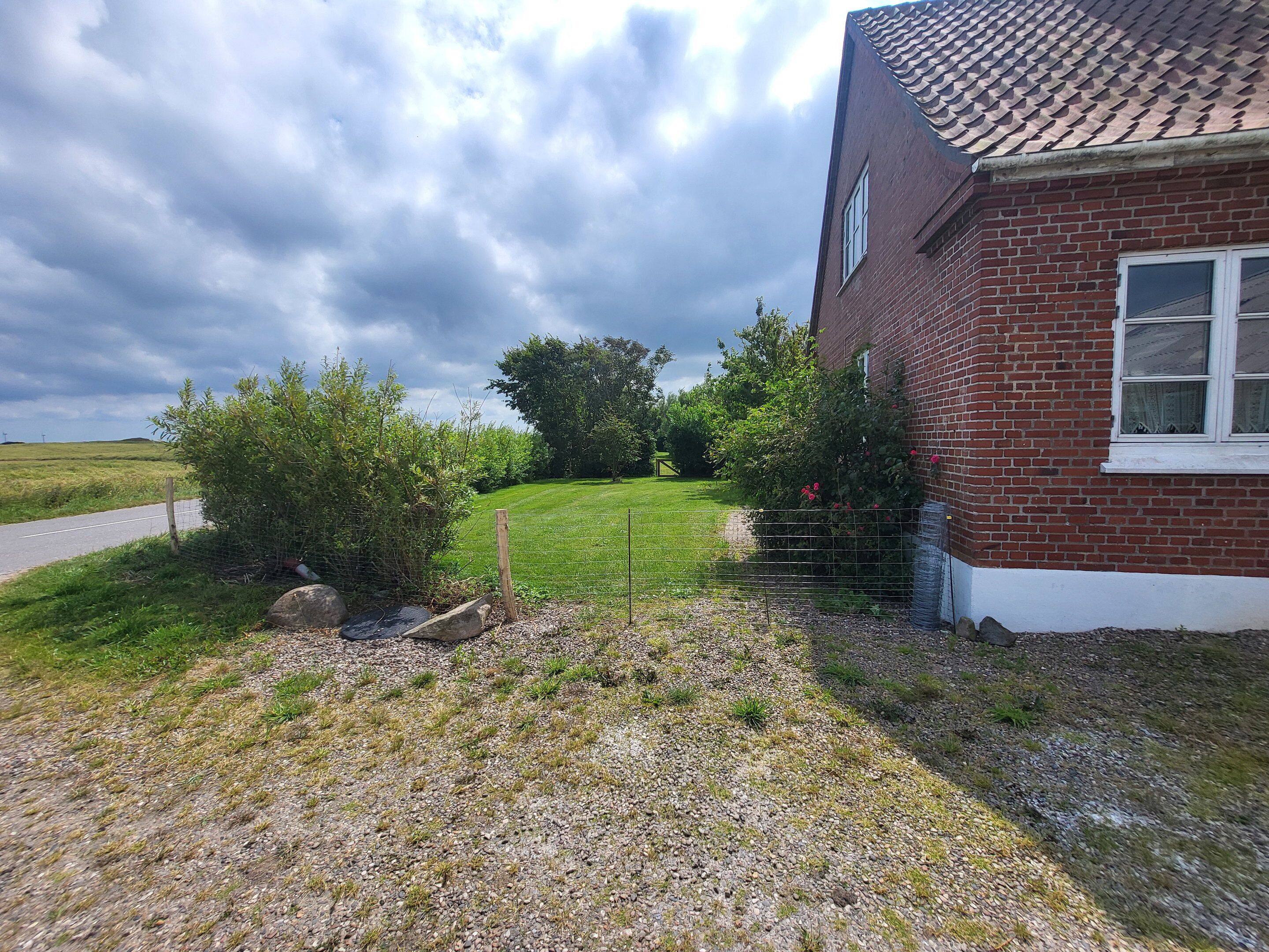 Ein Backsteinhaus mit Schotterauffahrt und einem umzäunten Garten.