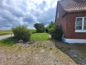 A brick house with a gravel driveway and a fenced yard.