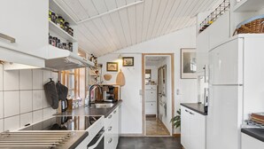 Eine moderne Küche mit weißen Schränken, einer Edelstahl-Arbeitsplatte und einem eingebauten Backofen.